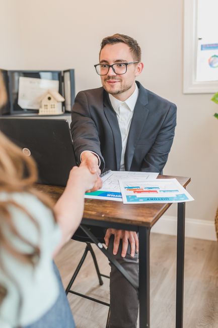 Real estate agent making a deal with his client at an office desk